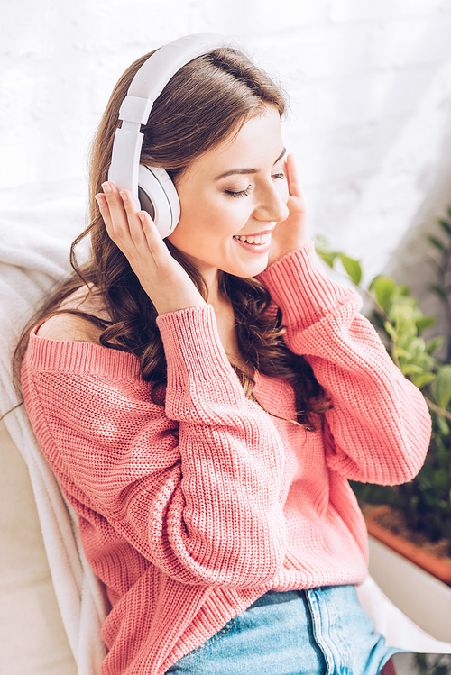 beautiful girl smiling and listening music in headphones with closed eyes