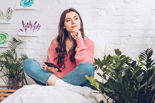 pretty dreamy girl looking away while sitting with crossed legs