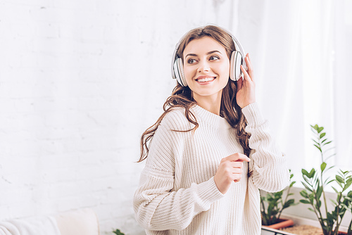 cheerful girl smiling and looking away while listening music in headphones
