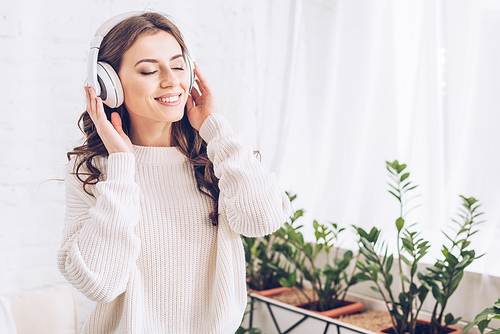 happy young woman listening music in headphones with closed eyes