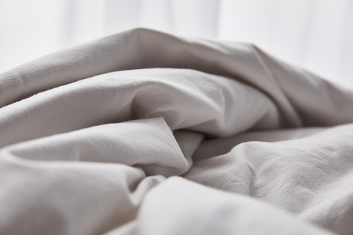 crumpled cotton white blanket in bed at morning