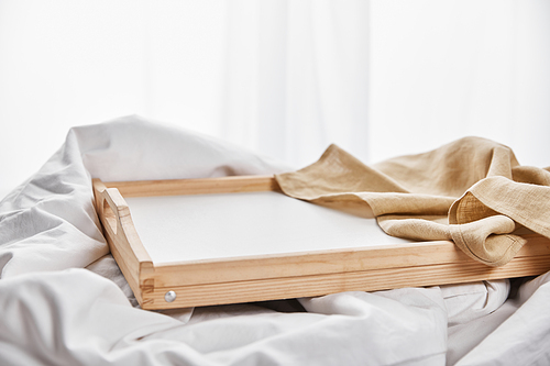 beige napkin on wooden tray in white bed