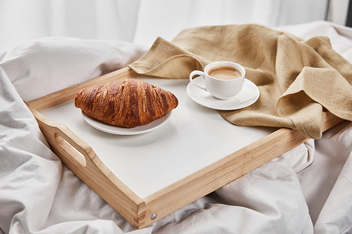 fresh croissant with coffee on wooden tray with napkin