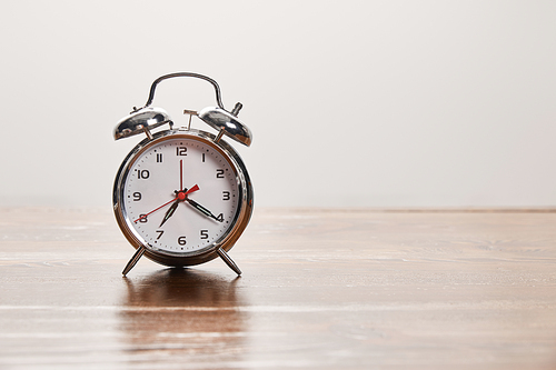 silver alarm clock on wooden brown table isolated on grey