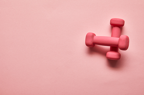 top view of pink dumbbells on pink background with copy space