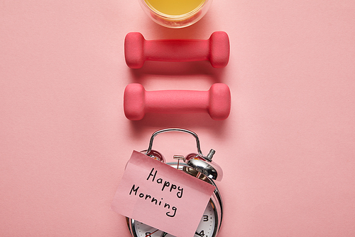 flat lay with happy morning lettering on silver alarm clock, pink dumbbells and orange juice on pink background