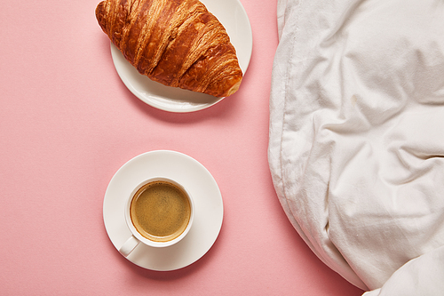 top view of blanket, coffee and croissant on pink background