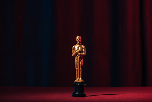 shiny golden oscar award on dark background