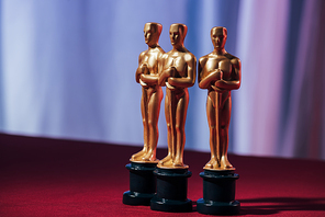 selective focus of golden oscar award statuettes with purple background