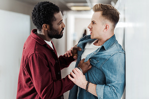 two multiethnic students fighting in corridor in college