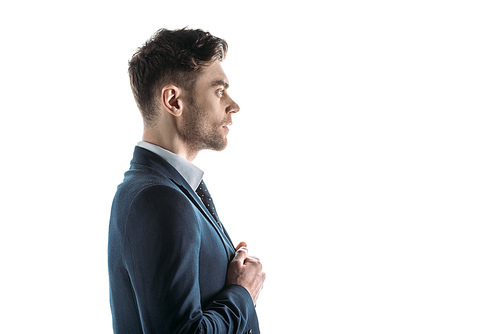 side view of handsome, serious businessman looking away isolated on white