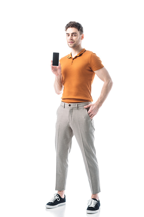 good-looking man with hand in pocket holding smartphone with blank screen isolated on white