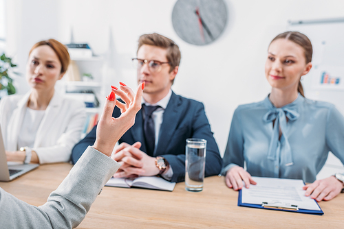 selective focus of female hand gesturing near recruiters during job interview