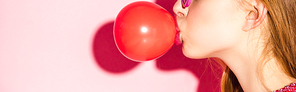 panoramic shot of girl blowing red bubble gum on pink