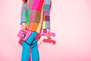 cropped view of woman in checkered dress holding retro phone on pink