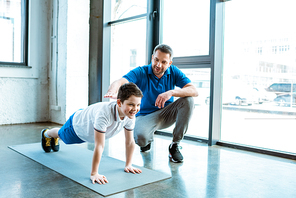 father helping son with push up exercise at gym with copy space