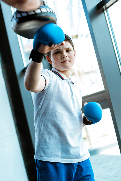 boy in boxing gloves training with coach at gym