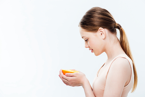 side view of teenager holding orange half isolated on grey