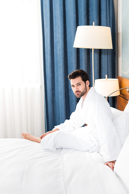 handsome bearded man  while sitting on bed in hotel room
