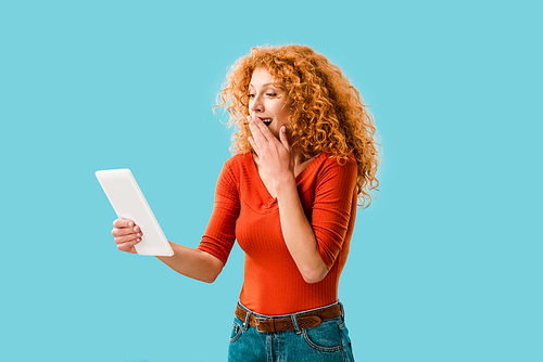 surprised woman using digital tablet isolated on blue