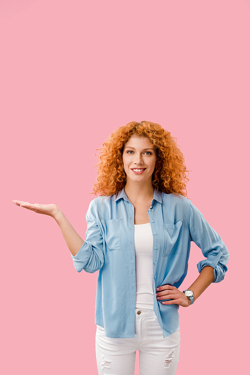 attractive redhead woman presenting something isolated on pink