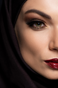 close up view of young Muslim woman in hijab with smoky eyes and red lips isolated on black