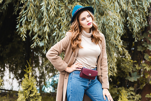 attractive woman in blue hat with hand on hip looking away