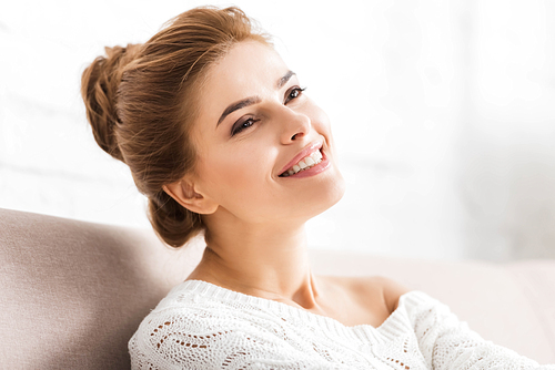 attractive woman in white sweater smiling and looking away