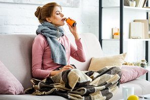 attractive and ill woman with grey scarf drinking cough syrup