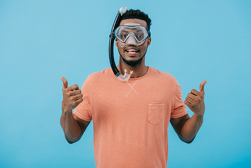 happy african american man in diving mask showing thumbs up isolated on blue