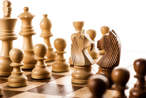 Selective focus of chess pieces on chessboard isolated on white