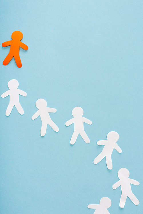 Top view of unique orange decorative man among white on blue background