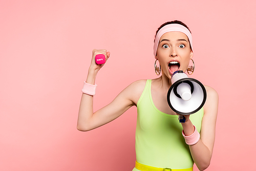 emotional sportswoman holding loudspeaker and dumbbell while screaming on pink