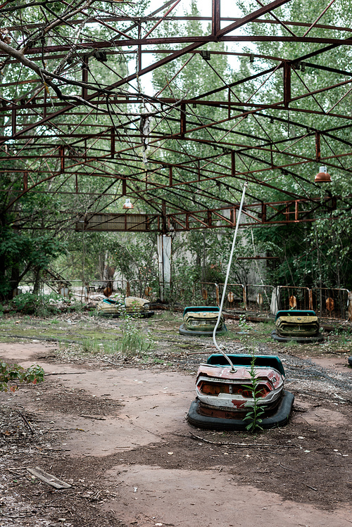 bumper cars in abandoned amusement park near trees