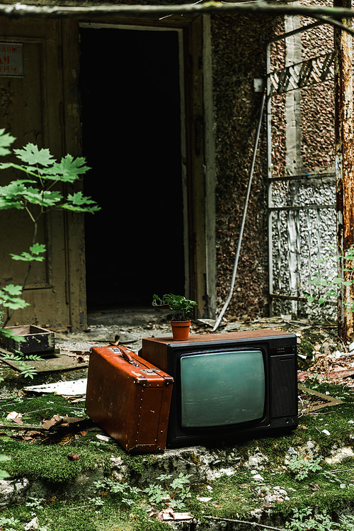 retro tv near suitcase on green stairs with mold