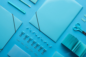 flat lay of paper binders, paper clips and various stationery isolated on blue