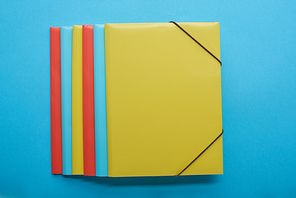 top view of red, blue and yellow paper binders on blue