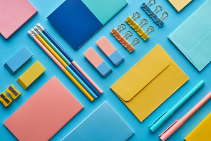 top view of notebooks and arranged colorful stationery isolated on blue