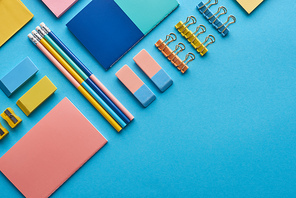 top view of notebooks and colorful stationery isolated on blue with copy space