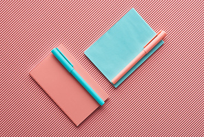 top view of pens and notebooks on textured pink