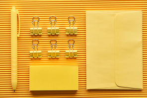 top view of pen, paper clips and arranged office stationery supplies on yellow