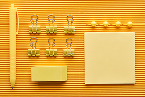 top view of pen, paper clips and colorful arranged office stationery supplies on yellow