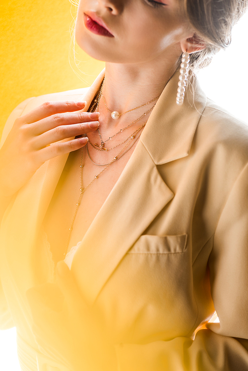 cropped view of woman touching necklace on white and yellow