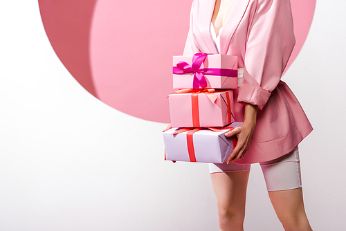 cropped view of woman holding presents on white and pink
