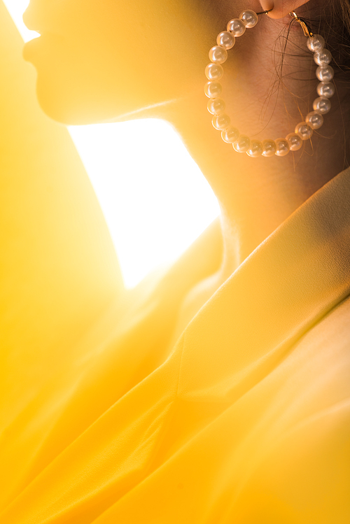 cropped view of stylish woman with pearl earring on white and yellow