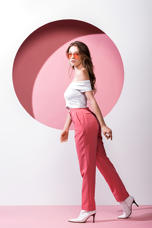 beautiful girl in sunglasses walking on white and pink