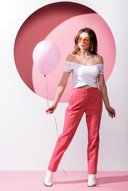 attractive woman holding balloon on pink and white