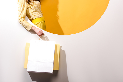 cropped view of young woman holding shopping bags on orange and white