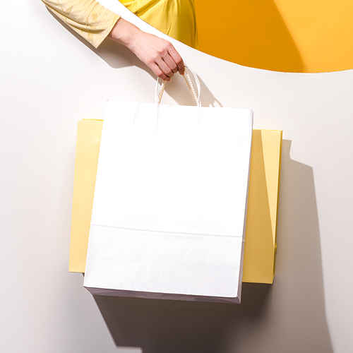 cropped view of woman holding shopping bags on orange and white