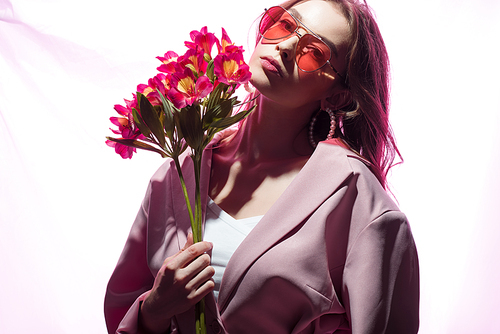 beautiful woman in sunglasses holding flowers on white